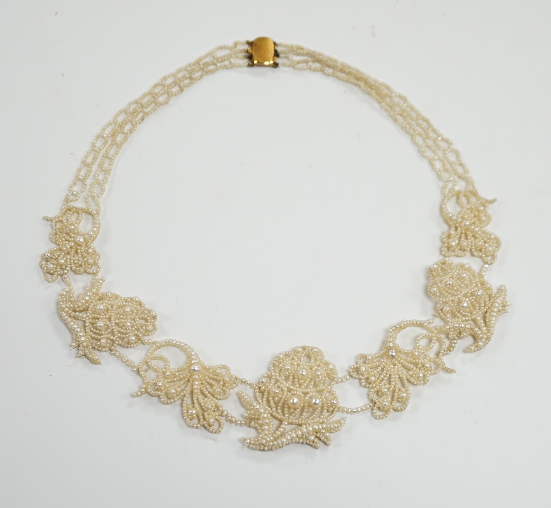 A cased Regency twin strand seed pearl choker necklace with scrolling floral motifs and yellow metal clasp, 34cm.